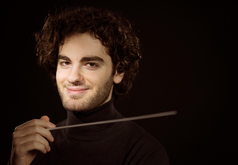 Man som håller i en dirigentpinne. Fotografi.