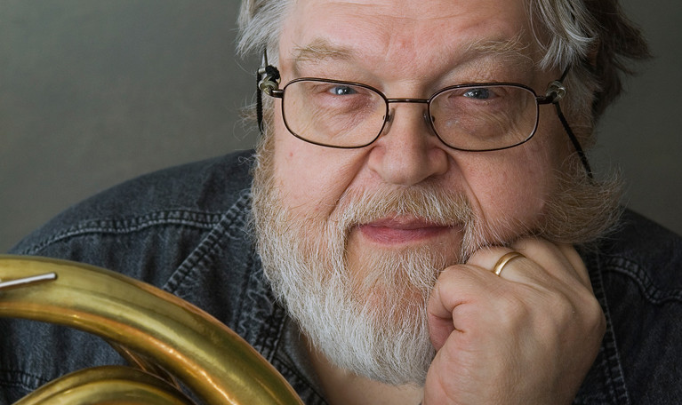 Man med horn i handen. Fotografi.