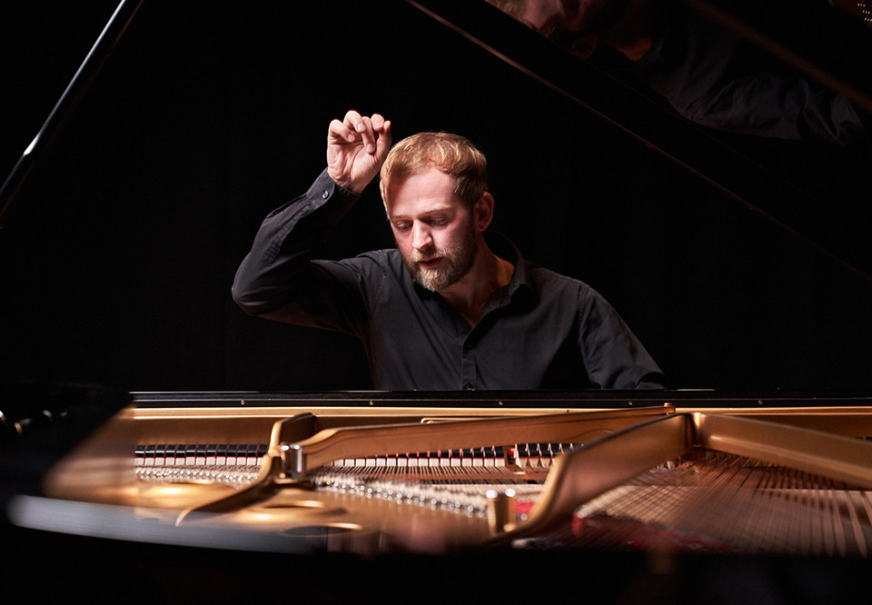 Man bakom ettt piano. Fotografi.