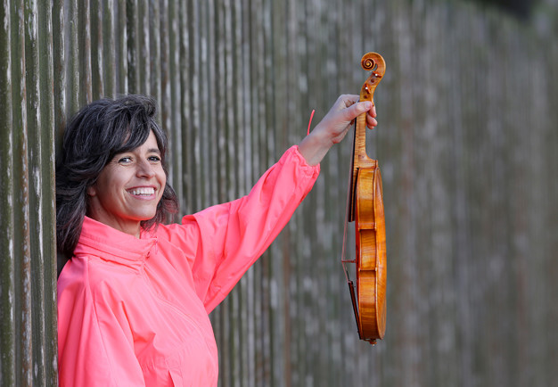 Kvinna som håller i en violin. Fotografi.