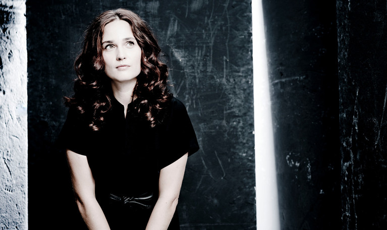 Kvinna som går framför en gul vägg. Fotografi.