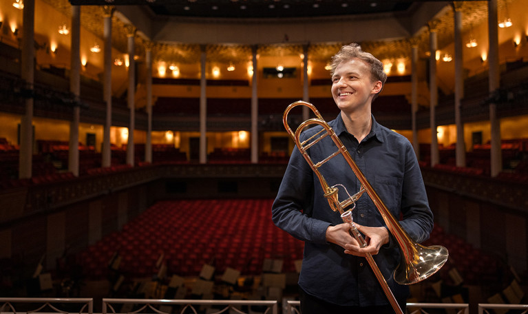 Man som håller i en trombon. Fotografi.