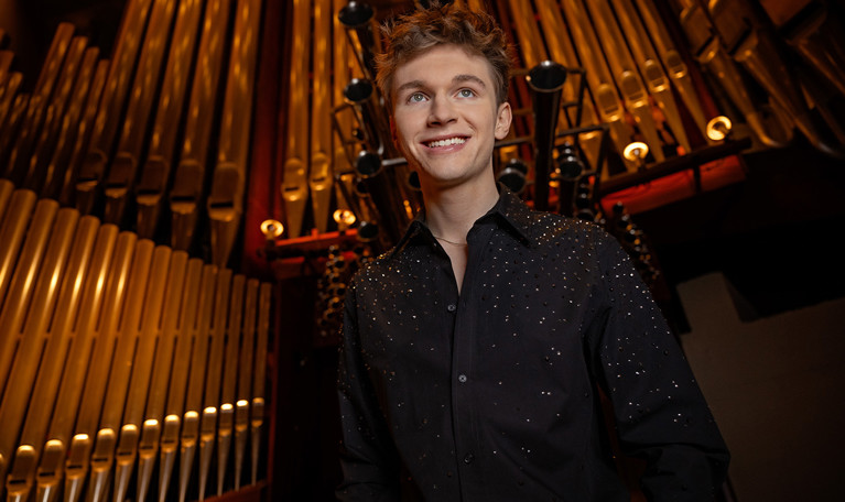 Ung kille framför orgel. Fotografi.