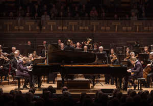 Två killar som spelar piano. Fotografi