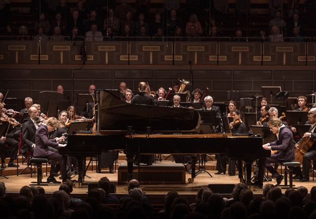 Två killar som spelar piano. Fotografi