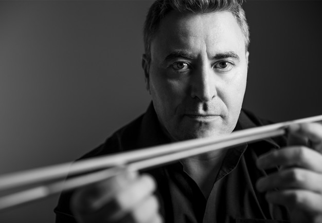 Man som håller i violin. Fotografi.