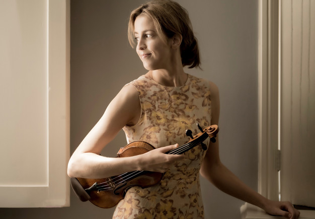 Ung kvinna som håller i en violin. Fotografi.